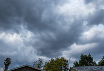 Heavy and dark thunderstorm clouds gather over a residential suburb in the Highveld region of South...