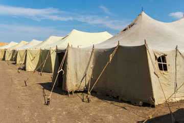 Group of canvas military tents in a sunny field