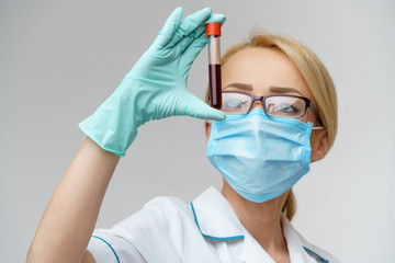 medical doctor nurse woman wearing protective mask and gloves - holding virus blood test