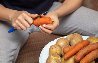 Girl peeling boiled carrots with a knife.