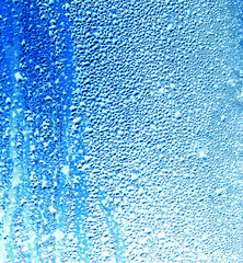 Drops of water on blue glass as an abstract background