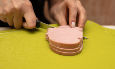 The girl cuts the sausage with a knife