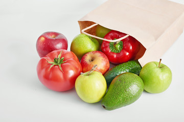 Paper bag with different vegetables isolated on white background.