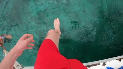 a traveler with red trunks jumping into the tropical sea from a FPV Persective in the Philippines