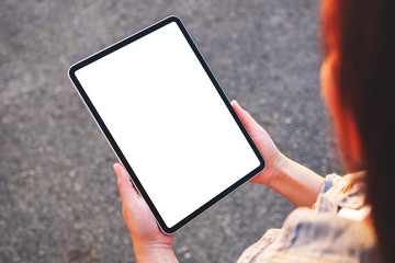 Top view mockup image of a woman holding a black tablet pc with blank white screen in the outdoors street background