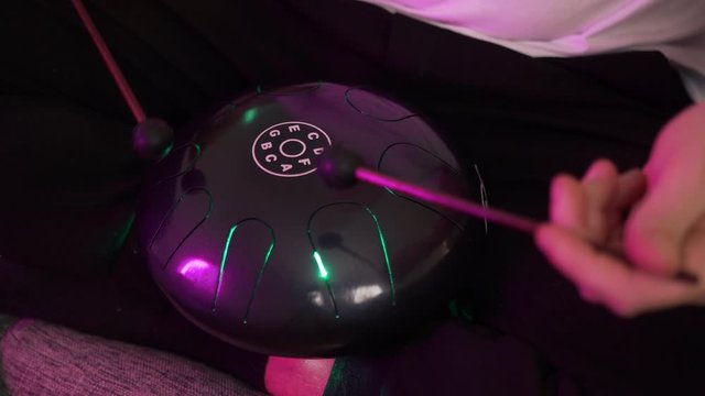 a man sits at home and plays on the hapi drum