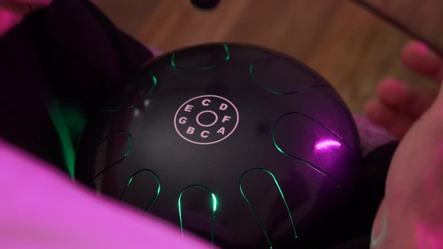 a man sits at home and plays on the hapi drum