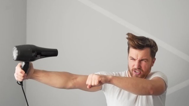 Young pretty man imagines he is a superman holding a hair dryer