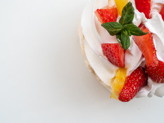 Close-up shot of creamy cake with fruits on white background. Space for text