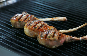 Three beef bone in rib eye steak with grill marks on grill.