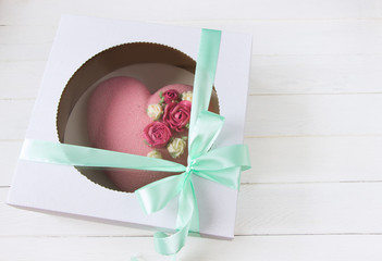 Delivery box with mousse cakes .Heart shape cake decoraited of pink roses. Box with bow, white background, sweet romantic gift. Sweets delivery consept