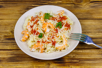 Spaghetti pasta with prawns, tomato sauce and parsley on wooden table