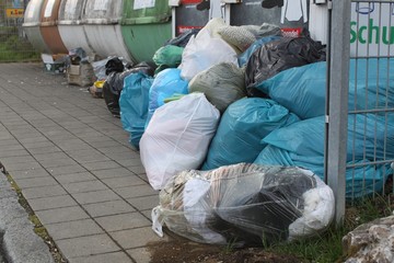 Abgelegter Müll im Grünen und vor Container