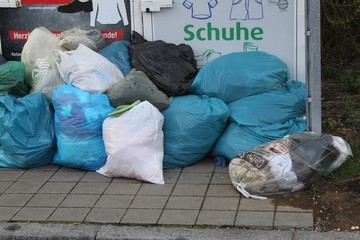 Abgelegter Müll im Grünen und vor Container