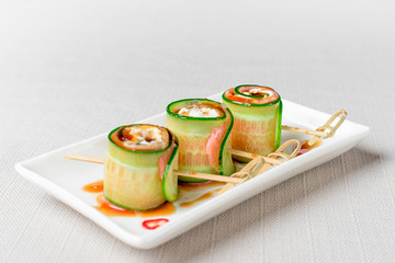 Roll cucumber and cream cheese on a wooden board