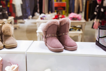Pink Ugg in the shop window, female winter warm shoes. Winter clothes, fashion and cold season concept.