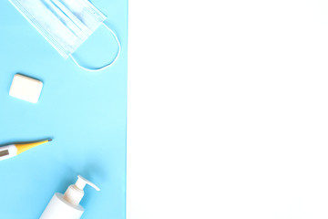 medical mask, disinfector, soap, pills on a blue background. flat lay