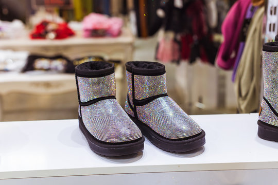 Silver Ugg in the shop window, female winter warm shoes. Winter clothes, fashion and cold season concept.