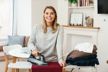 Photo of cheerful woman housewife smiling while ironing clothes