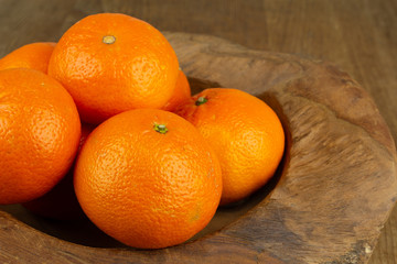 fresh mandarin orange fruits in a wooden bowl