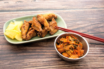 Fried chicken wings with Korean pickle kimchi on a wooden table
