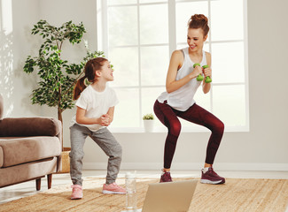 Active woman with daughter doing exercises at home