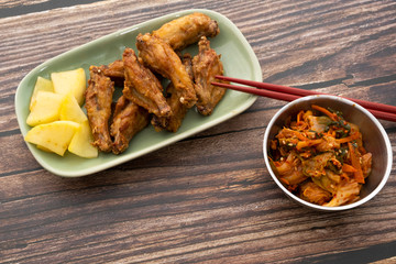 Fried chicken wings with Korean pickle kimchi on a wooden table