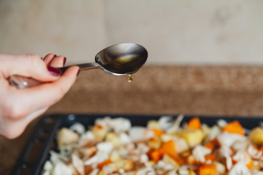 Hand pours vegetable oil from tablespoon