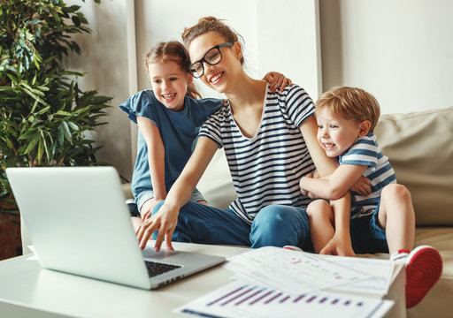 Young woman with kids working with laptop at home.