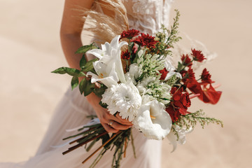 Bride is holding beautiful wedding bouquet of white flowers and anthurium