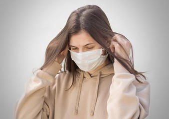 The girl puts on a medical mask. Close up. Isolated on a grey background