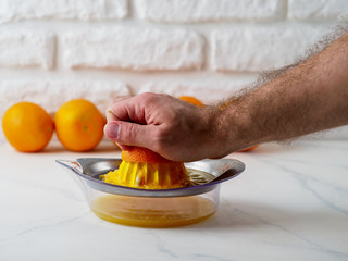 Manual juicer with man's hand squeezing orange.