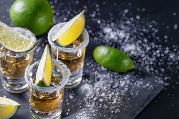 Tequila with lime on dark table with sprinkled salt
