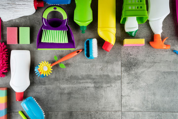 Spring house cleaning. Colorful cleaning kit on gray tiles floor. Top view.