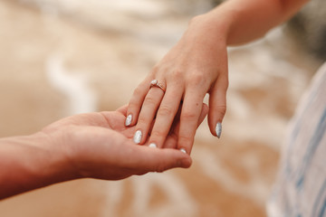 Young men  proposing to his girlfriend at the beach, hands close up. A man offers the hand and heart of a loved one on a tropical island