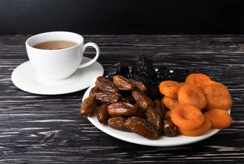Dried fruits and a cup of tea on a black background