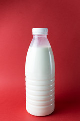 Bottle of milk on a red background. Vertical orientation