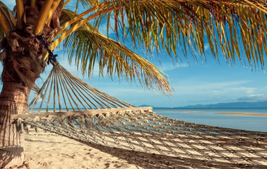 Naklejka premium Hammock under a palm tree overlooking a tropical island