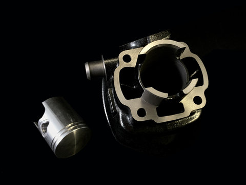 Cylinder and piston on a black background. Piston system from a moped. Motor parts from a motorcycle.