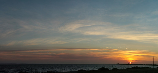 Fototapeta premium Panorama of the sun setting over a beach coastal scene along the bay near Melbourne, Victoria, Australia