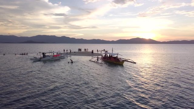 Aerial View of a group of traditional Philippines boats float at sunset with beautiful warm colors in the sky
