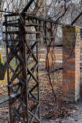 Red brick and wooden columns of the gazebo in the spring. Fragment of an ancient pergola in the...