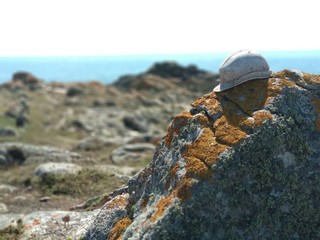 old bruised helmet on a rock next to the sea