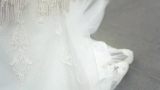 Tilt up from the hem of a wedding gown to the bouquet