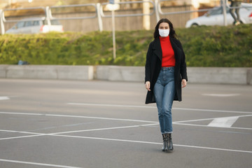 A masked girl is walking along the street. Coronavirus infection COVID-19