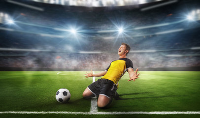 Fototapeta na wymiar Ball on the green field in soccer stadium. Professional Soccer Player Does Knee Slide Celebrates Awesome Victory after Scoring a Goa