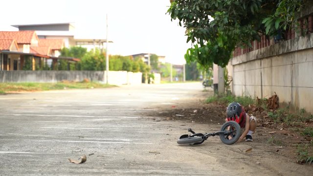 Asian boy about 4 years old playing dirt while exercise with balance bike while his mother running in the background