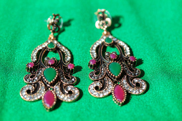  earrings inlaid with semi-precious stones at green background
