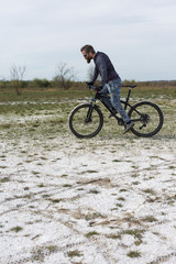 Fototapeta premium Sports brutal bearded guy on a modern mountain bike. A cyclist in a salt deserted place by the lake.