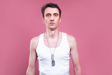 Serious young man skinny and pale guy posing on camera. Isolated over pink background. Man stand...